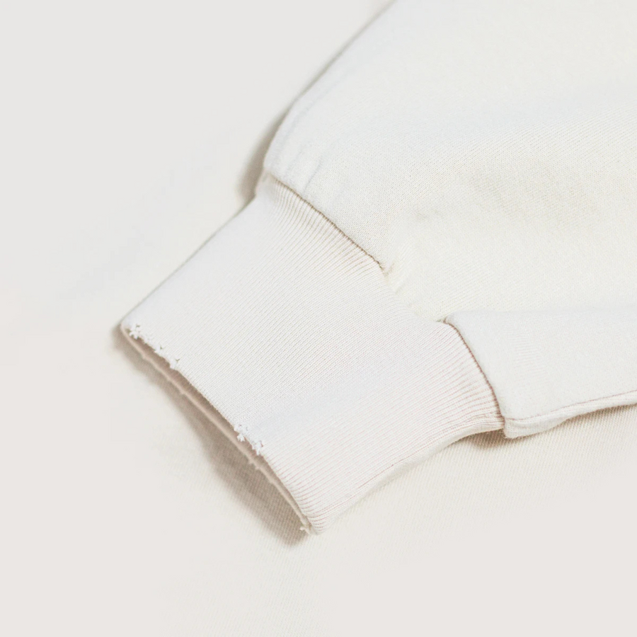 Detalle del puño acanalado con acabado desgastado en sudadera retro crema